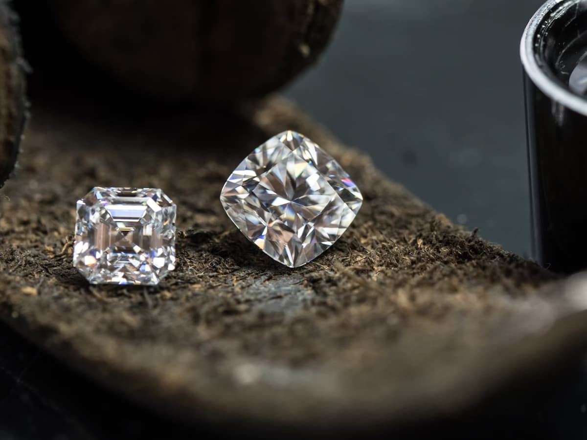 An asscher and a cushion cut sitting side by side on a leather parcel pad